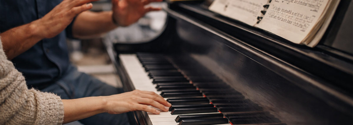 Weibliche und männliche Hände auf dem Klavier