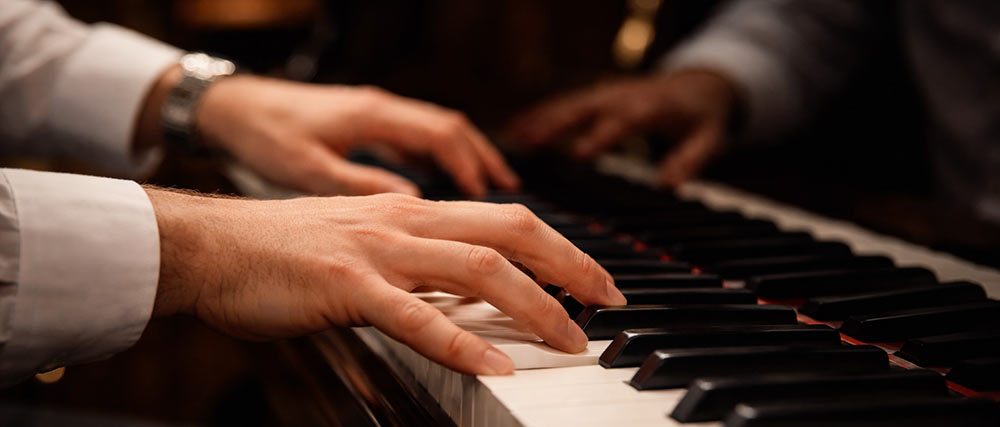 Nahaufnahme von Händen, die auf einem Flügel Klavier spielen