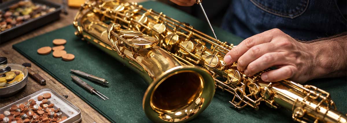 Reparatur und Wartung eines Saxophons mit Werkzeugen auf einer Werkbank in einer Instrumentenwerkstatt
