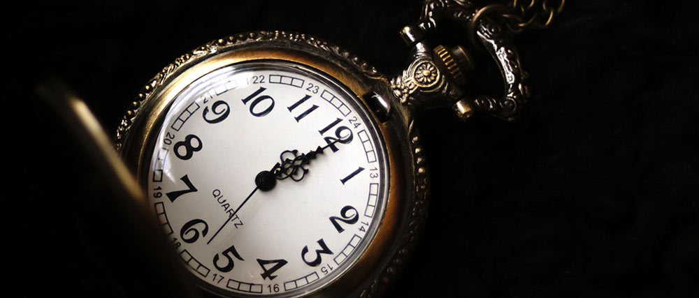 Nahaufnahme einer klassischen Taschenuhr mit römischen Zahlen auf dunklem Hintergrund
