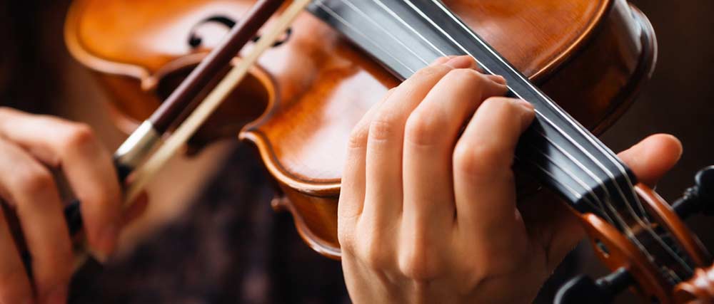 Hände spielen Violine mit Bogen auf dem Griffbrett in Nahaufnahme