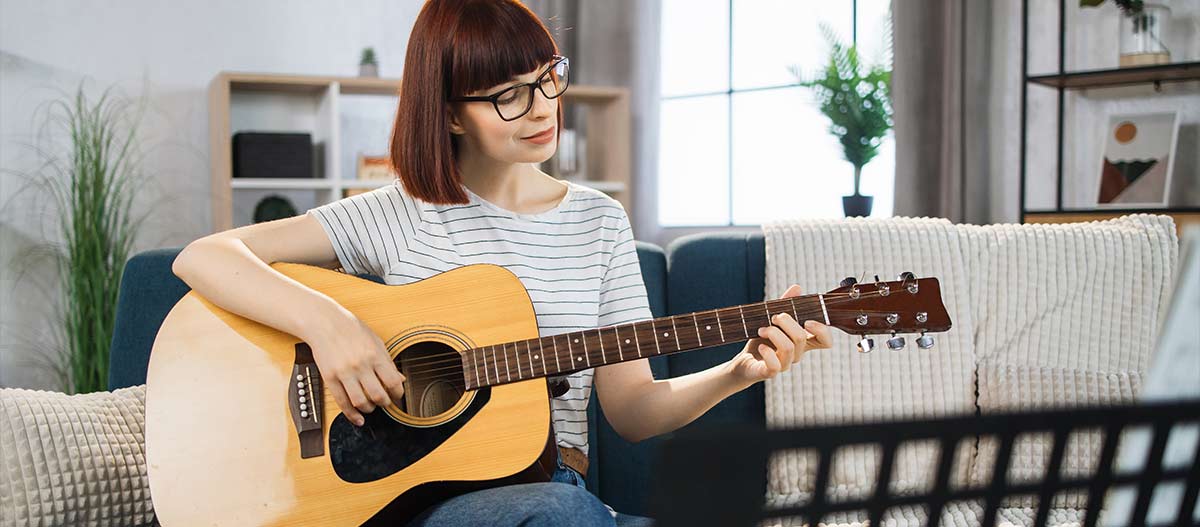 Eine Frau die zu Hause Gitarre spielt