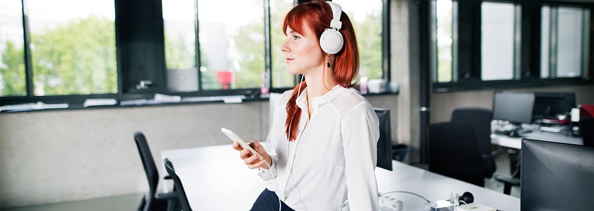 Frau im Büro hört Musik