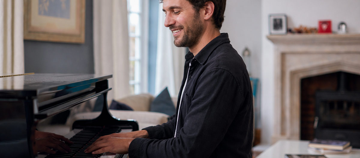 Lächelnder Mann spielt Klavier im Zimmer