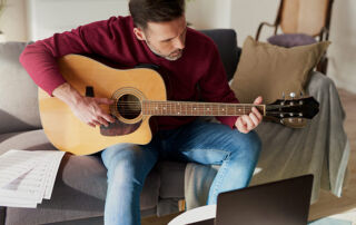 Mann spielt Gitarre auf dem Sofa