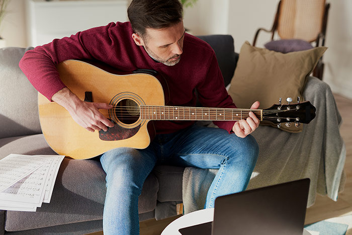 Mann spielt Gitarre auf dem Sofa