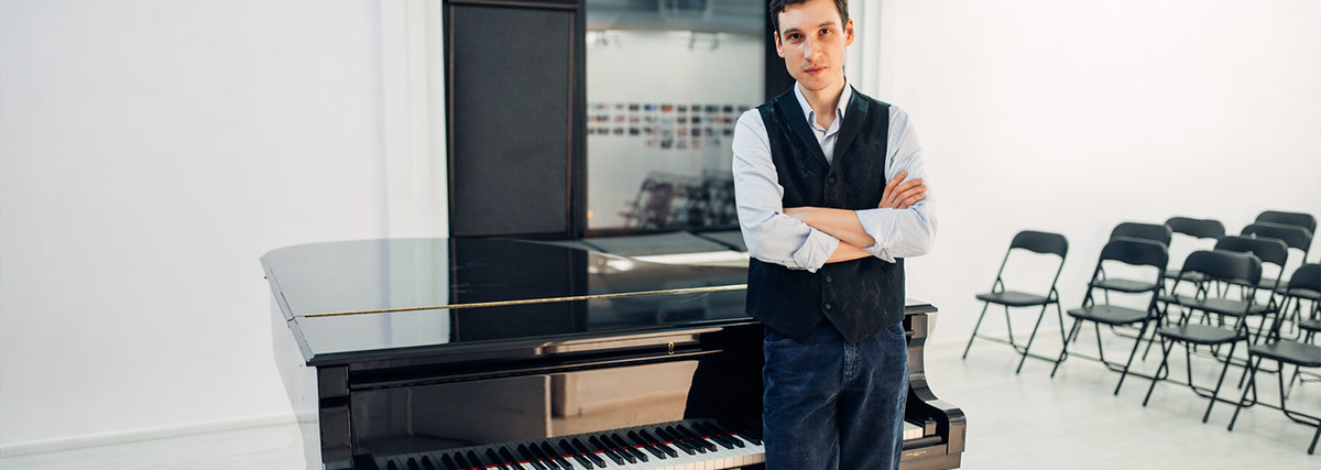 Musiklehrer, der neben dem Klavier steht