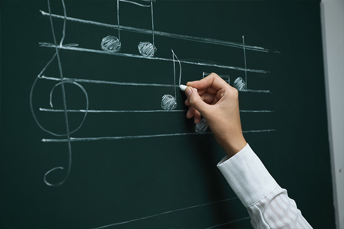 Musiknoten von Hand an die Tafel schreiben