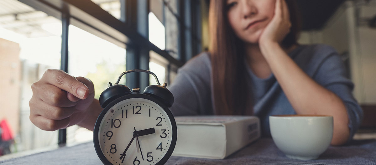 Traurige Frau, die auf eine Uhr zeigt