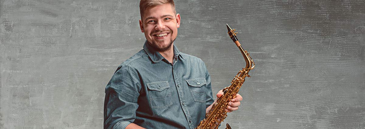 Ein Mann hält glücklich ein Saxophon