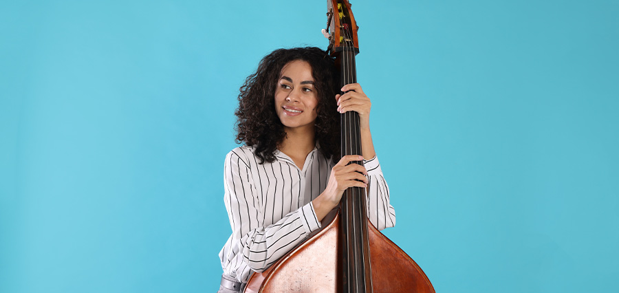 Erwachsene Bassistin mit Kontrabass vor blauem Hintergrund für professionellen Bassunterricht