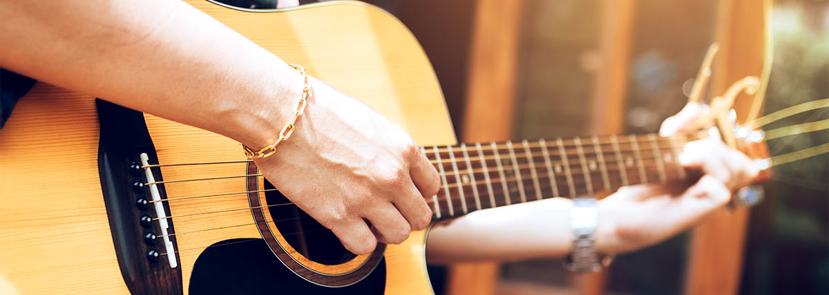 Männliche Hände spielen Akustikgitarre