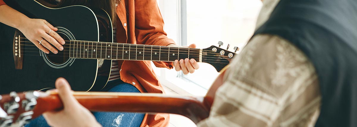 Zwei Erwachsene spielen Gitarre