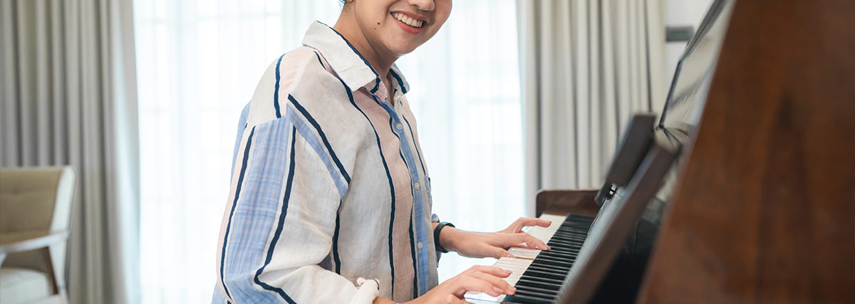 Eine Frau, die lächelnd Klavier spielt