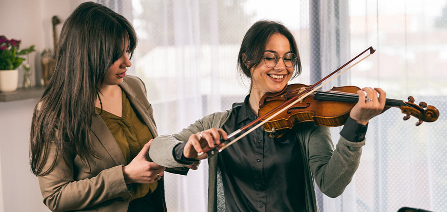 Deutsche Geigenlehrerin gibt einem erwachsenen Anfänger Geigenunterricht und unterstützt ihn bei Technik und musikalischem Ausdruck