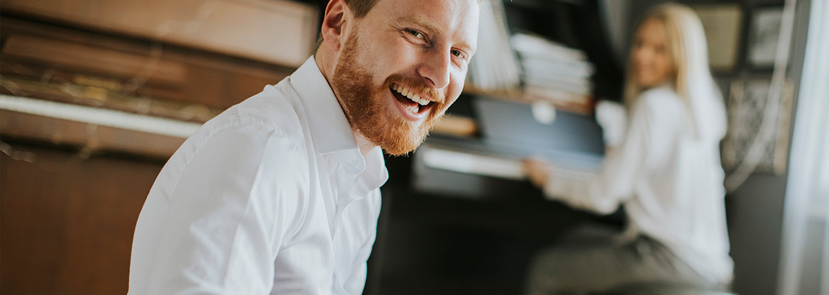 Man smiling with pianist in the background