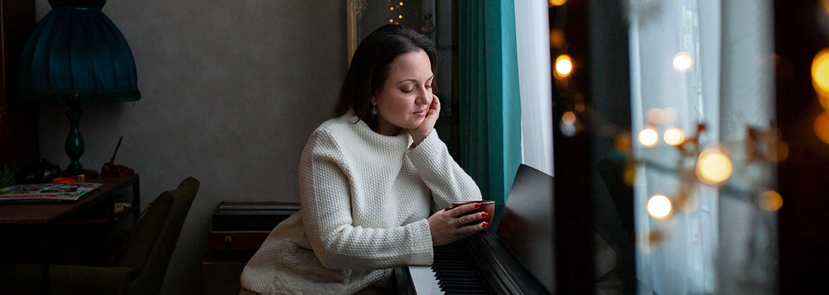 A woman drinking coffee beside the piano
