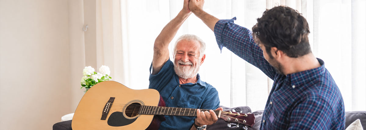 Mann spielt Gitarre, während ein anderer Mann die Arme hebt