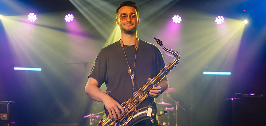 Saxophonist mit Tenorsaxophon auf einer Bühne unter farbigem Scheinwerferlicht
